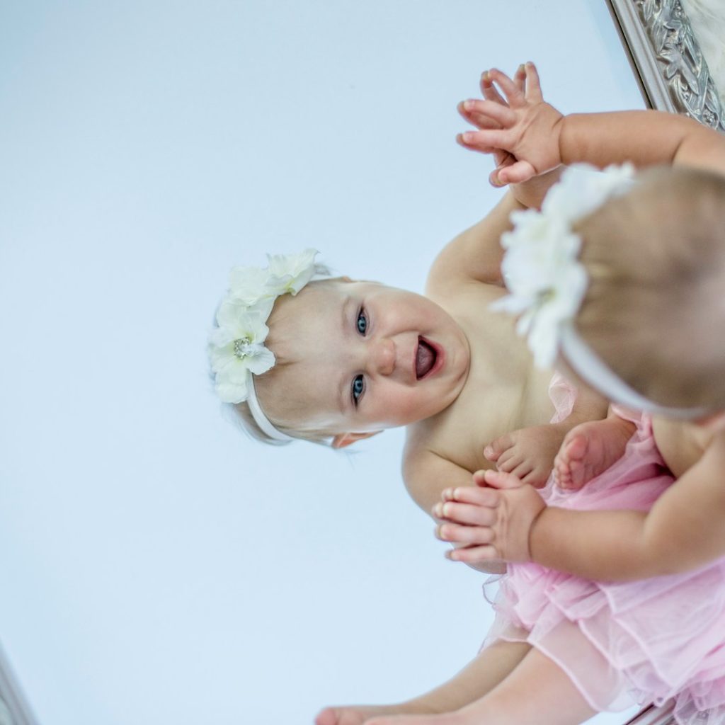 toddler facing mirror while smiling
